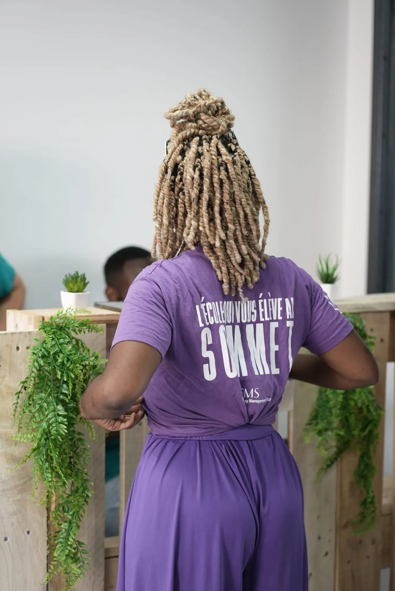 Une étudiante d’EMS de dos, t-shirt « L’école qui vous élève au sommet »
