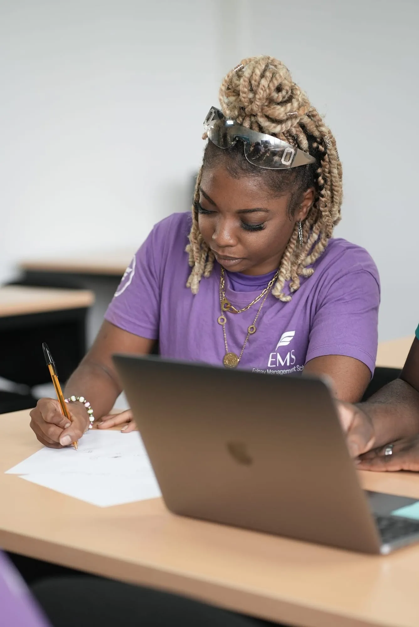 Une étudiante d’EMS prend des notes à côté de son ordinateur