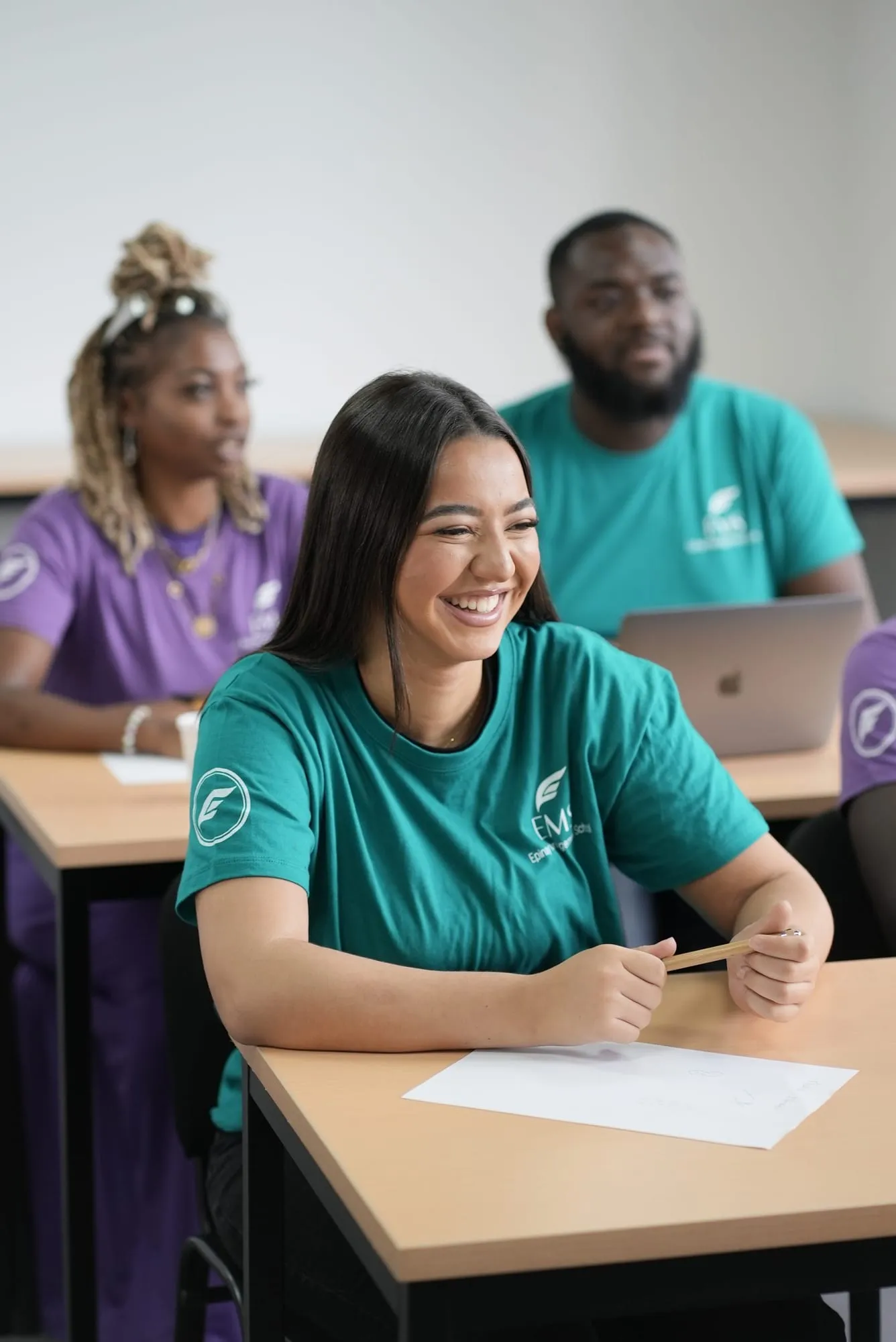 Une étudiante d’EMS sourit en cours, entourée de camarades en t-shirt de l’école
